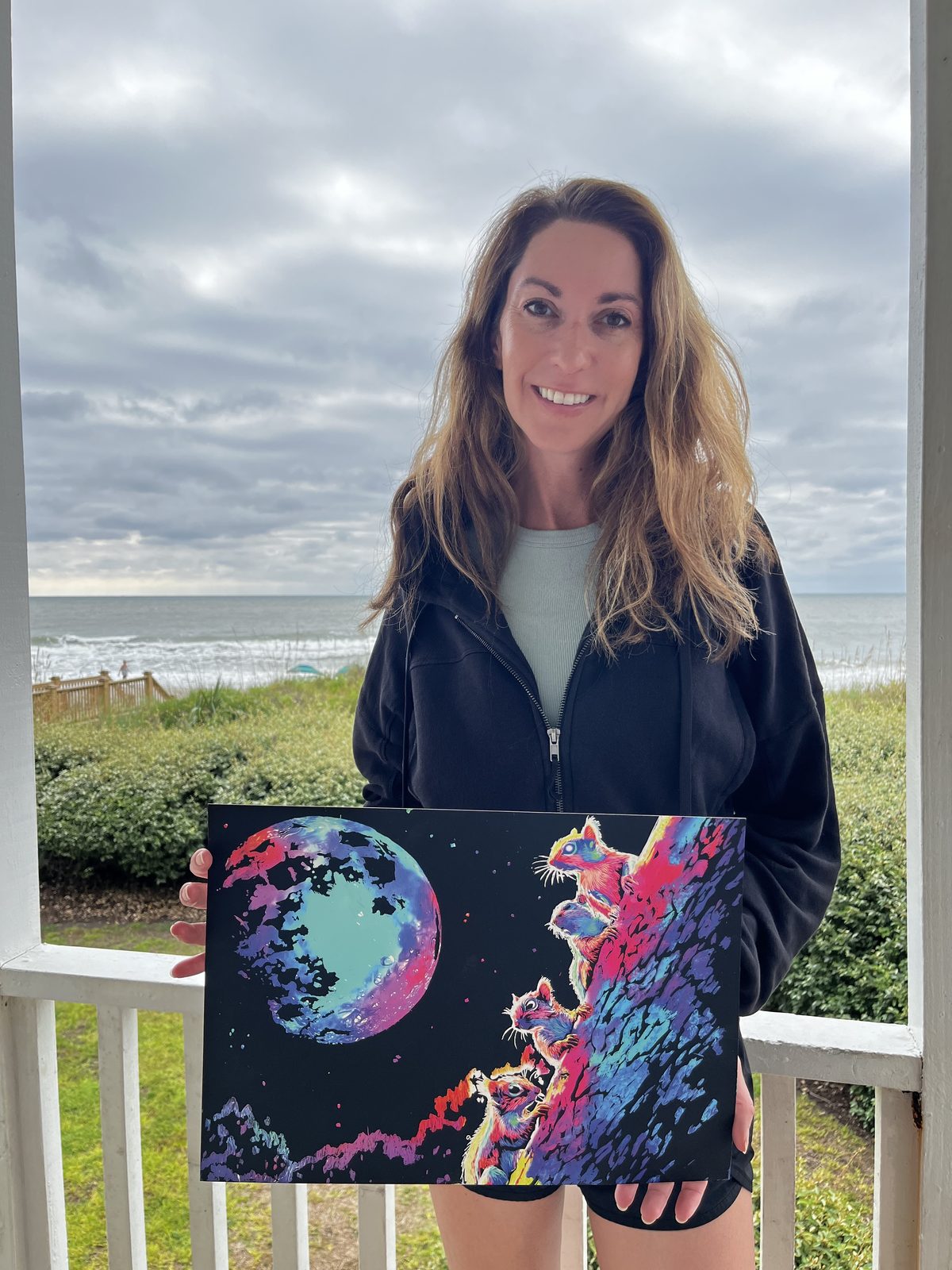 Customer with a finished moon canvas on a coastal balcony